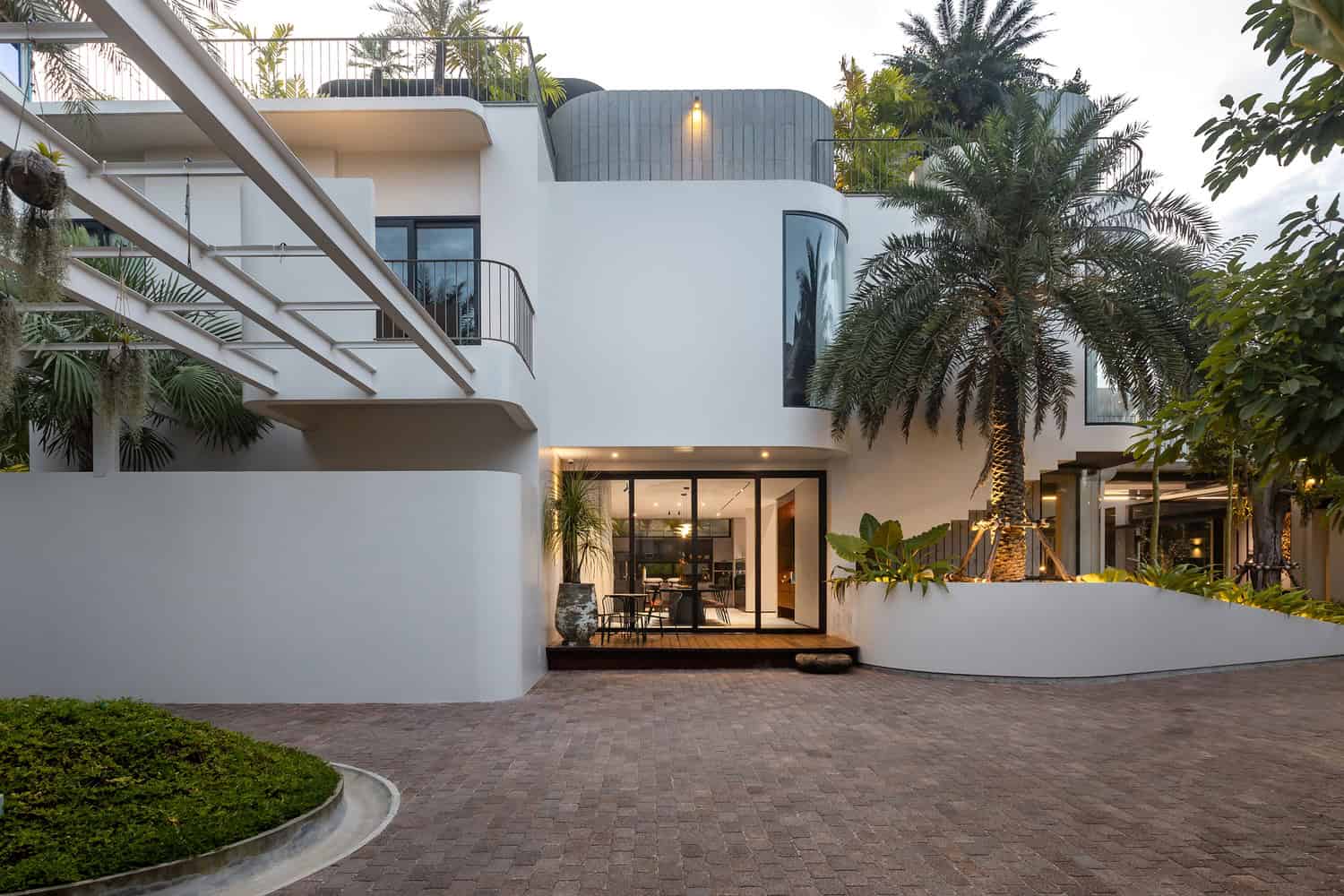 Wat Bo House by UAD Architects courtyard facade with pergola and palm at evening in Cambodia