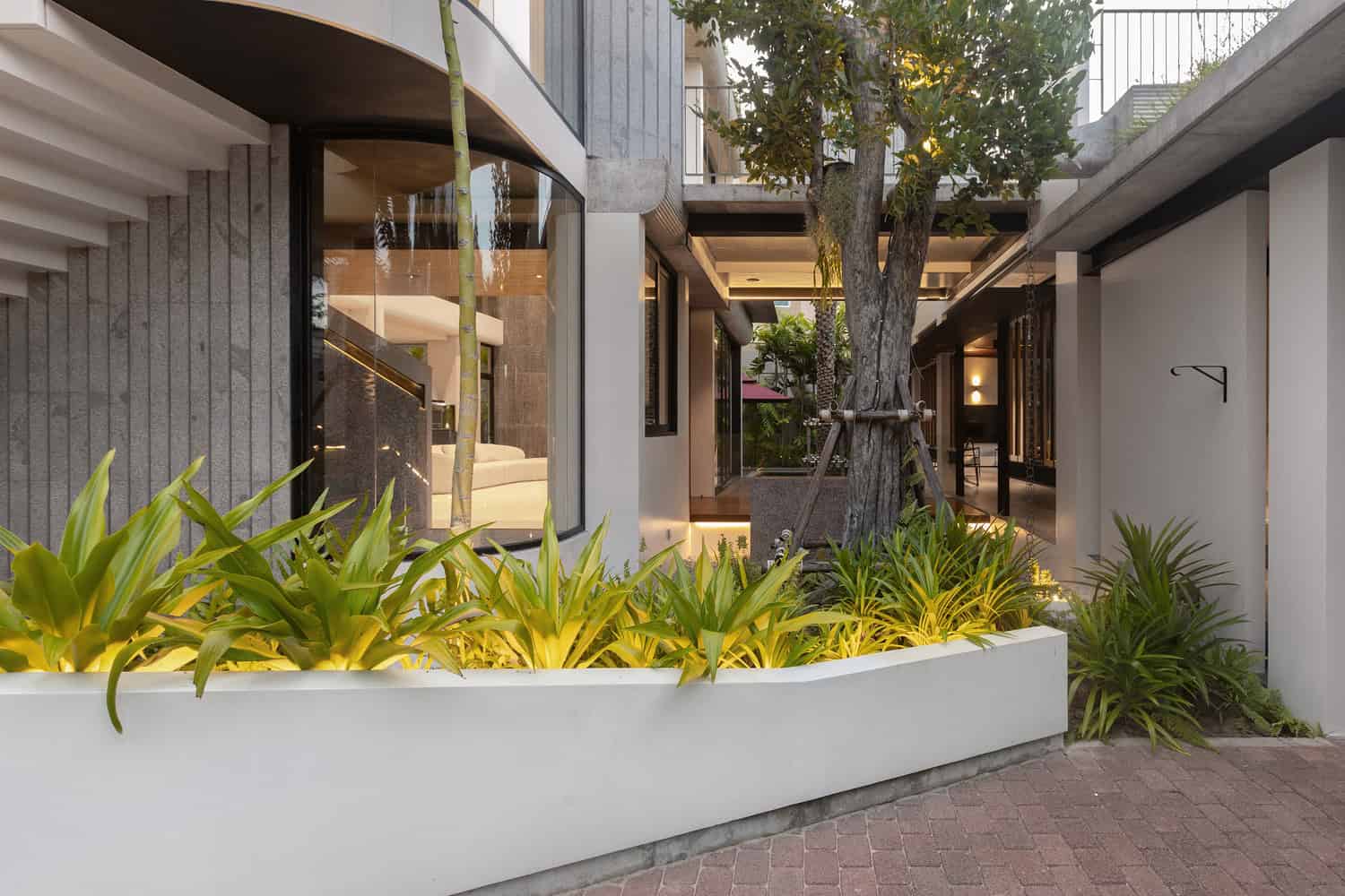 Wat Bo House by UAD Architects courtyard with lush planting and glass facade in Cambodia