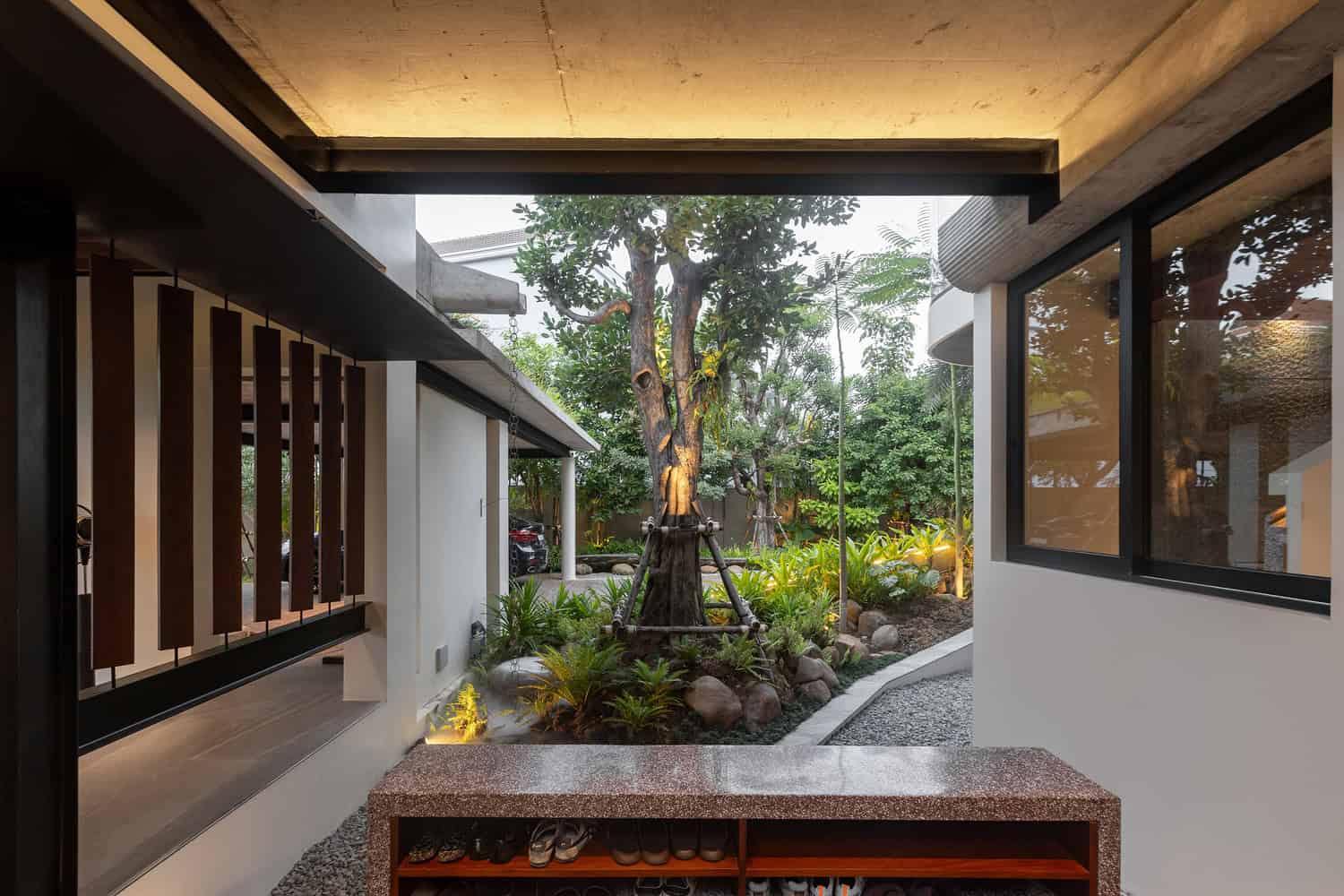 Wat Bo House by UAD Architects covered entry with shoe bench overlooking the garden in Cambodia