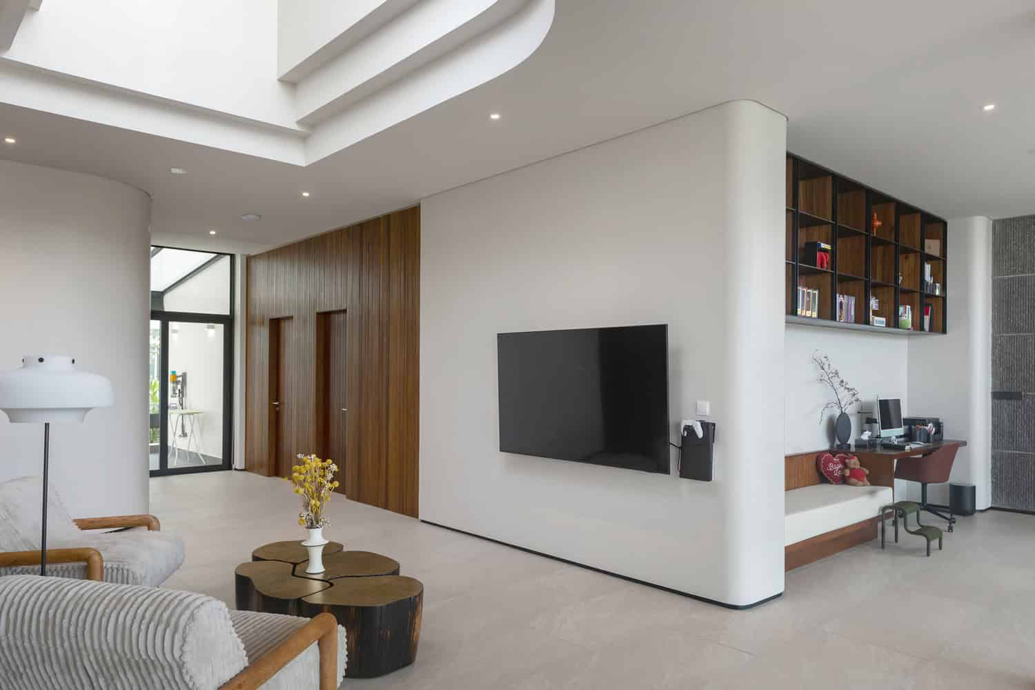 Wat Bo House by UAD Architects double height living room with stone tv wall in Cambodia