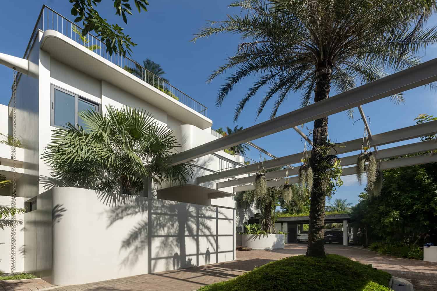 Wat Bo House by UAD Architects front facade with pergola and palm trees in Cambodia