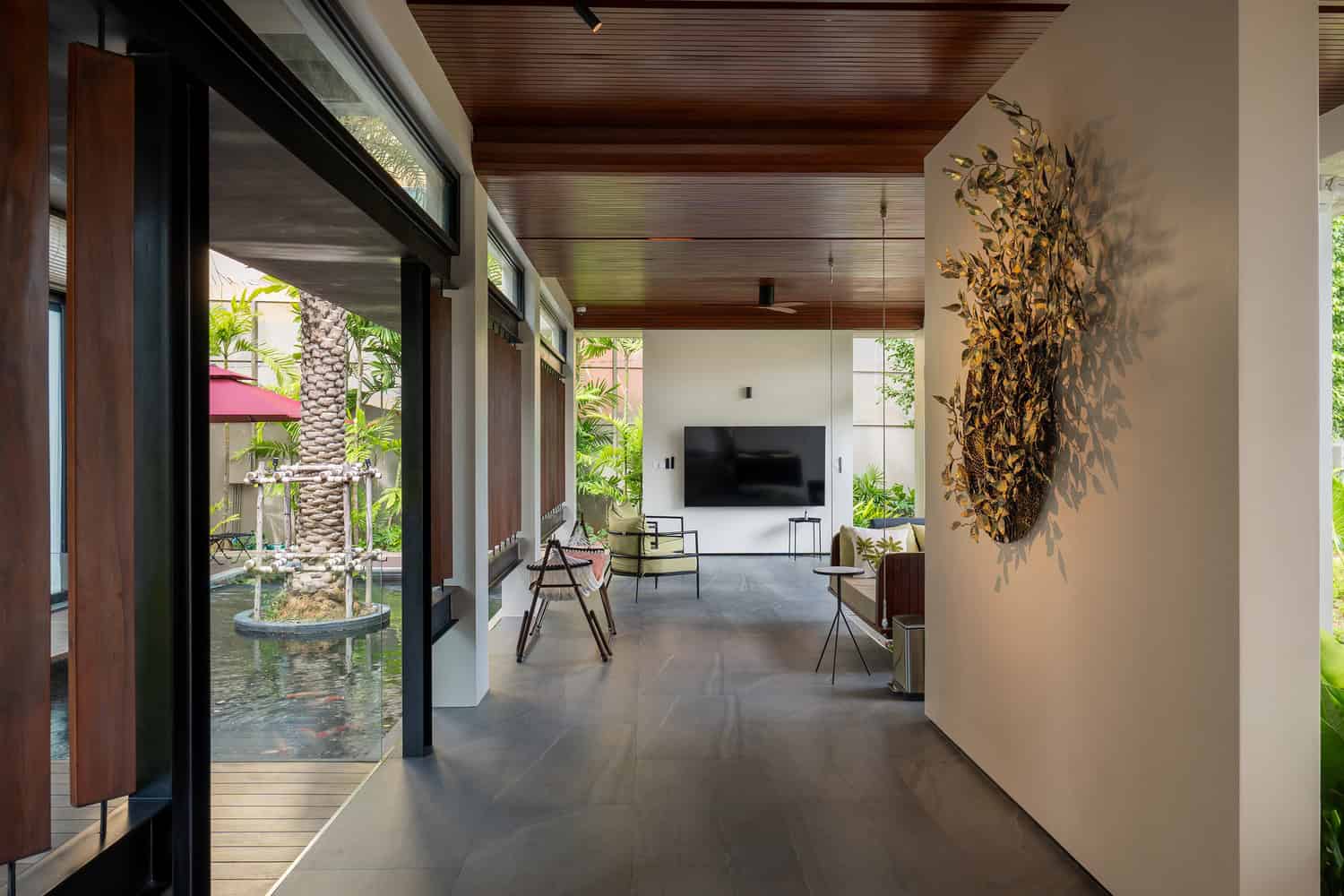 Wat Bo House by UAD Architects interior corridor opening to pond in Cambodia