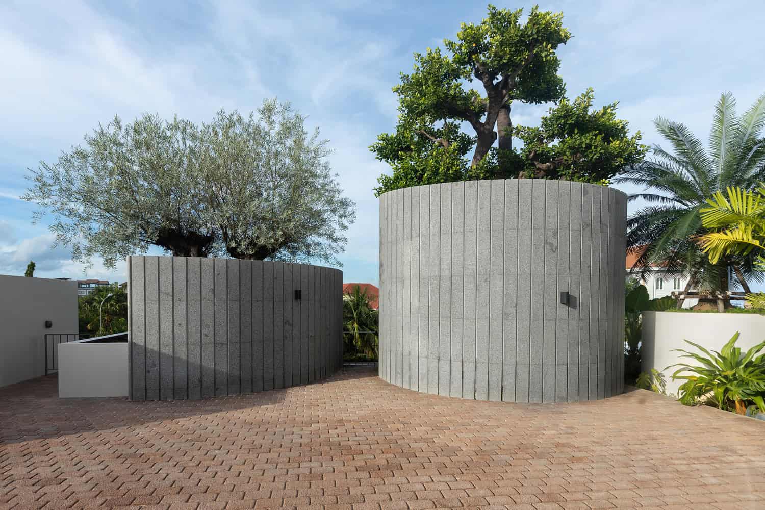Wat Bo House by UAD Architects rooftop terrace with cylindrical stone planters and trees in Cambodia