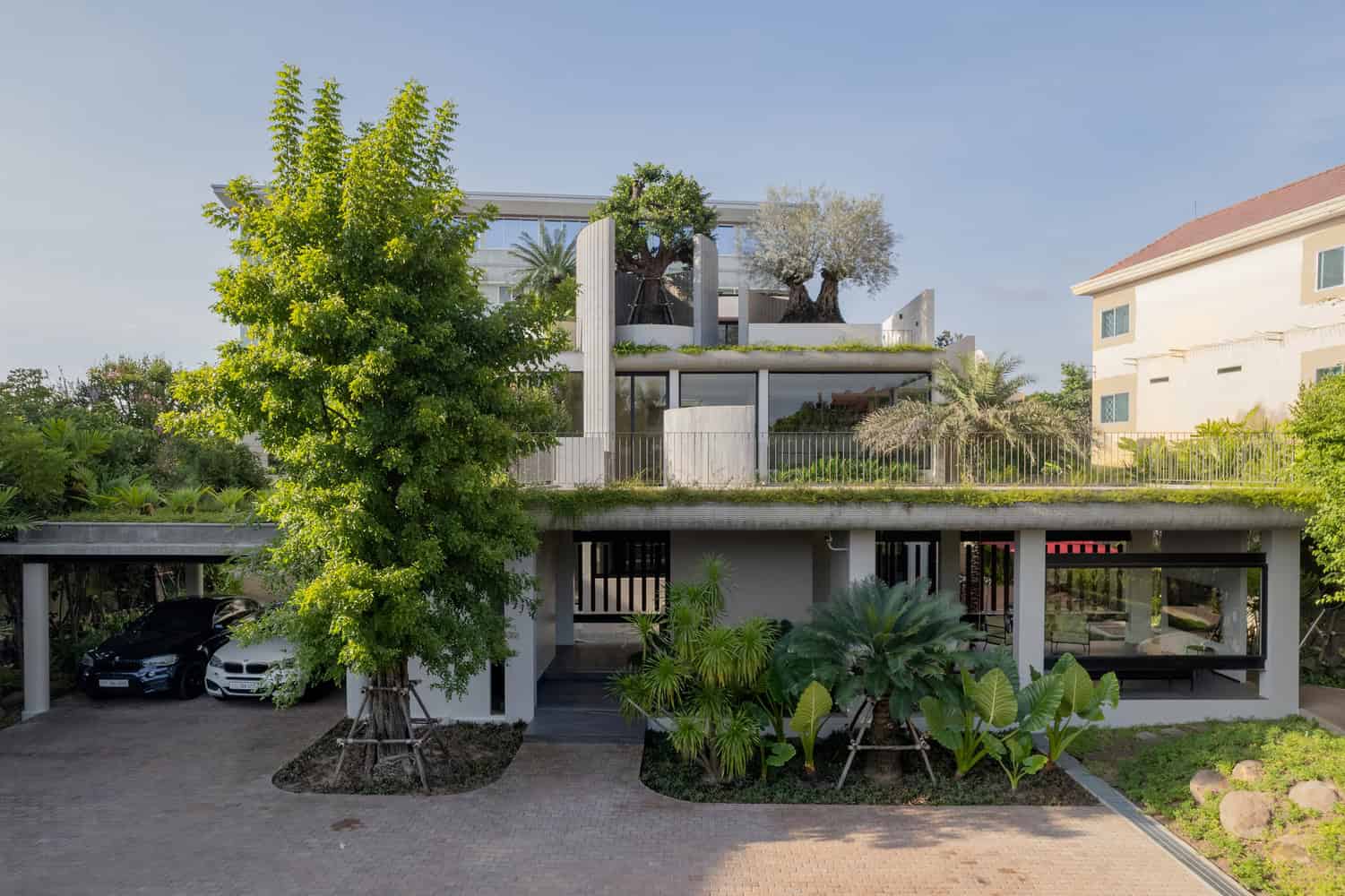 Wat Bo House by UAD Architects street elevation with carport and lush rooftop garden in Cambodia