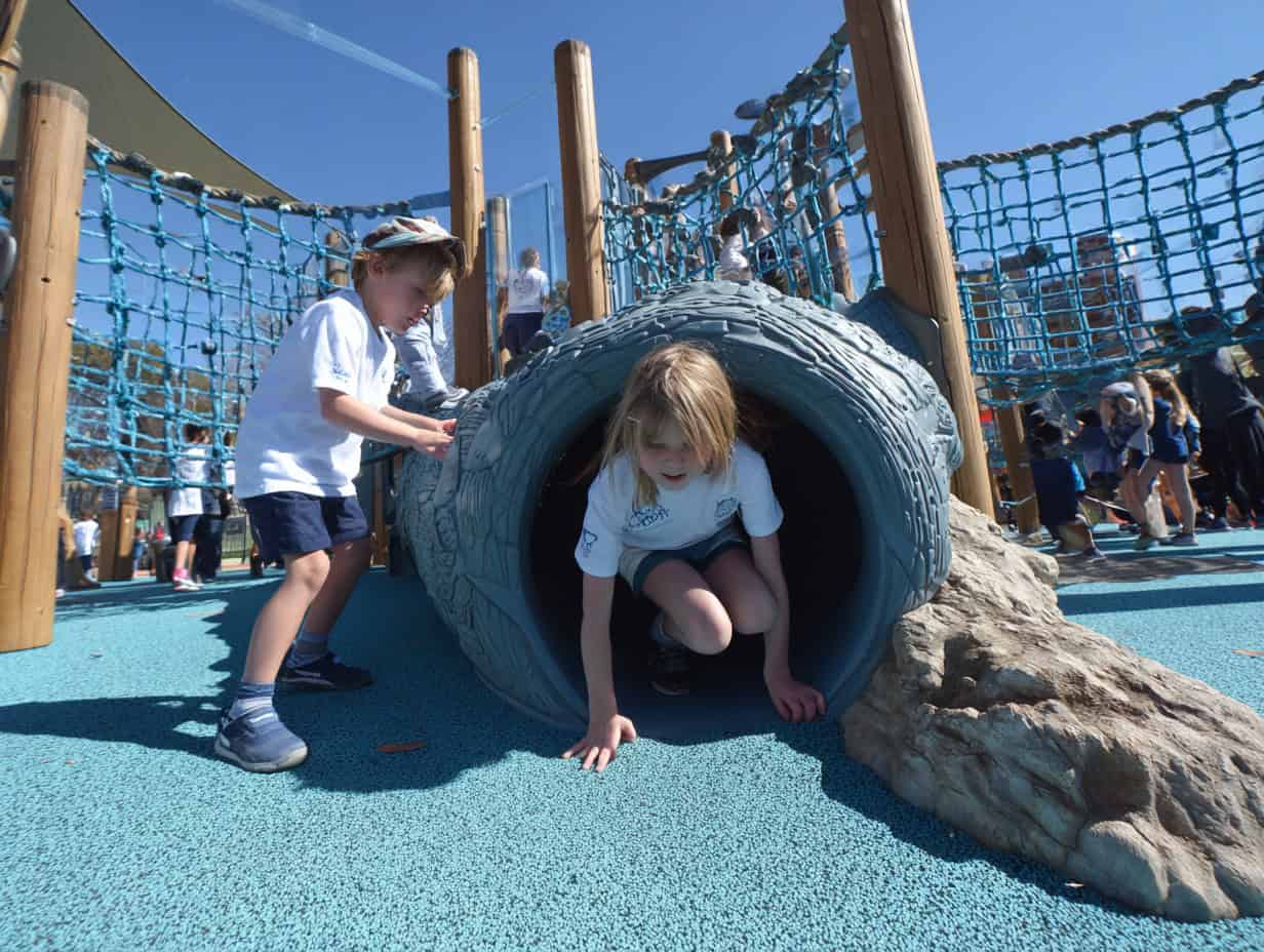 Children playing in inclusive playground climbing tunnel