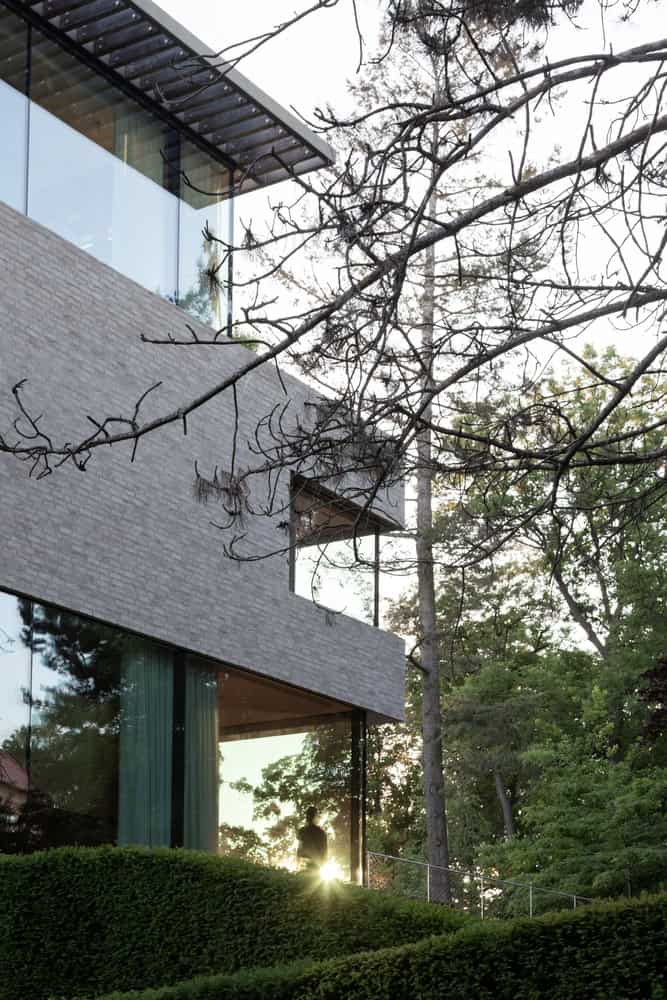 Villa Vista by Znameni Ctyr Architekti, corner glazing with sunflare and silhouetted figure in the window