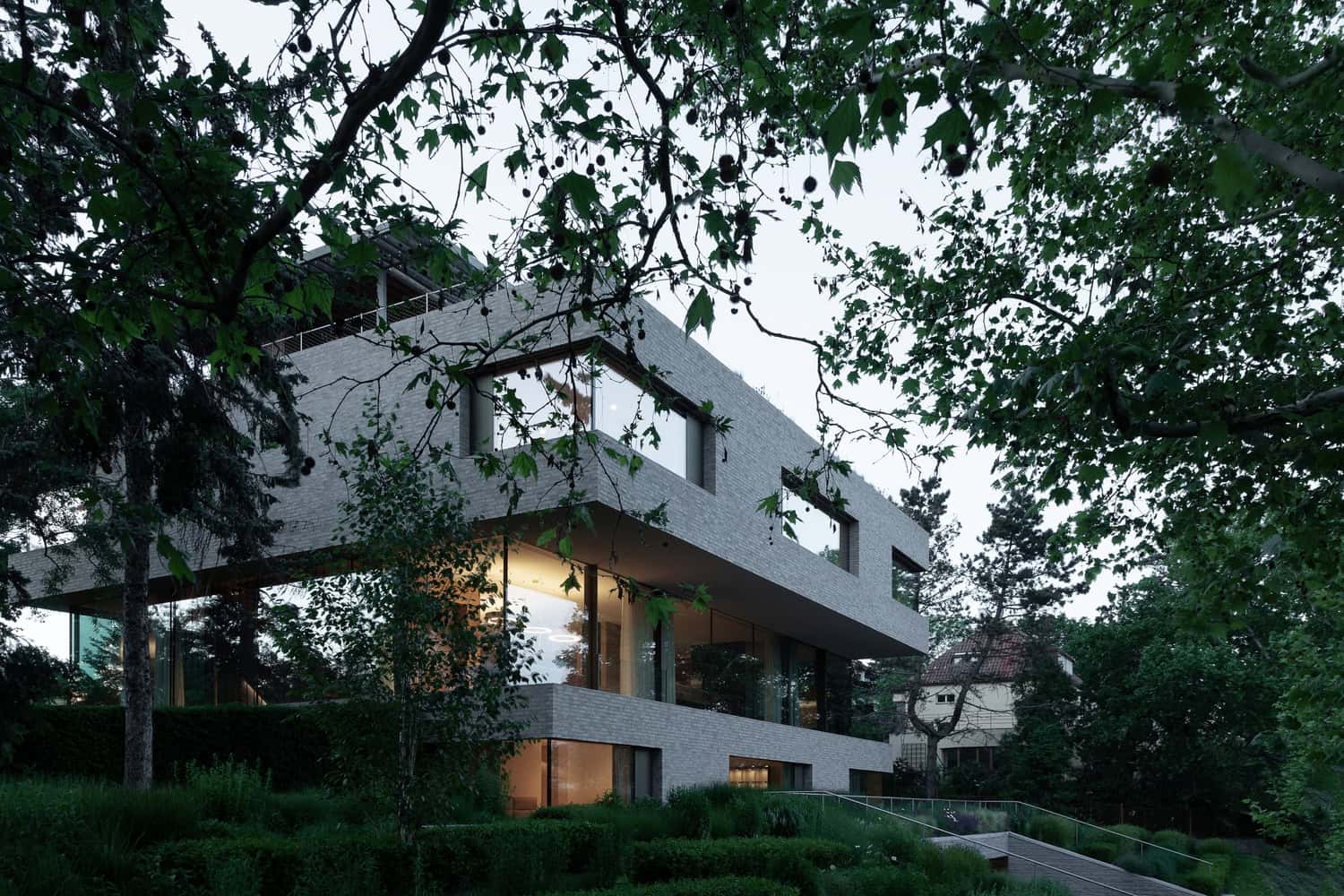 Villa Vista by Znameni Ctyr Architekti, distant view of the villa framed by mature trees and garden in Prague