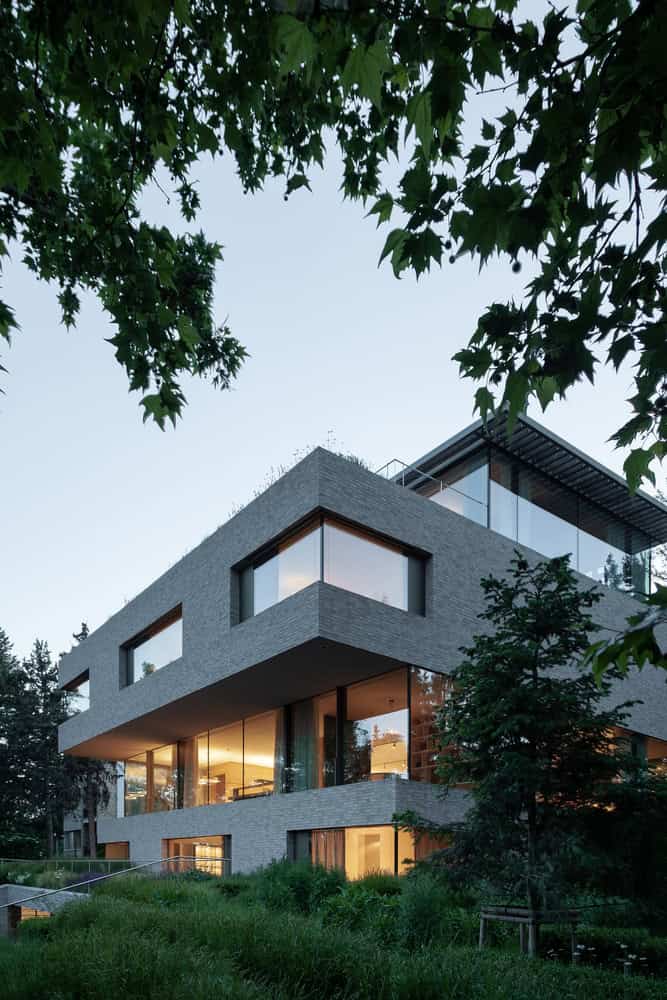 Villa Vista by Znameni Ctyr Architekti, angled brick volumes with glowing interiors at dusk in Prague