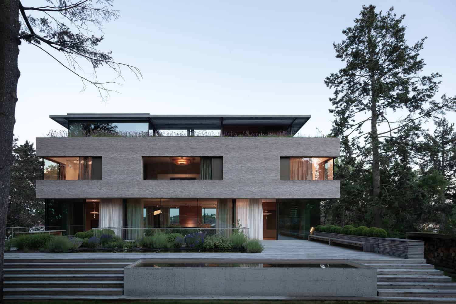 Villa Vista by Znameni Ctyr Architekti, front elevation at dusk with reflecting pond and steps in Prague