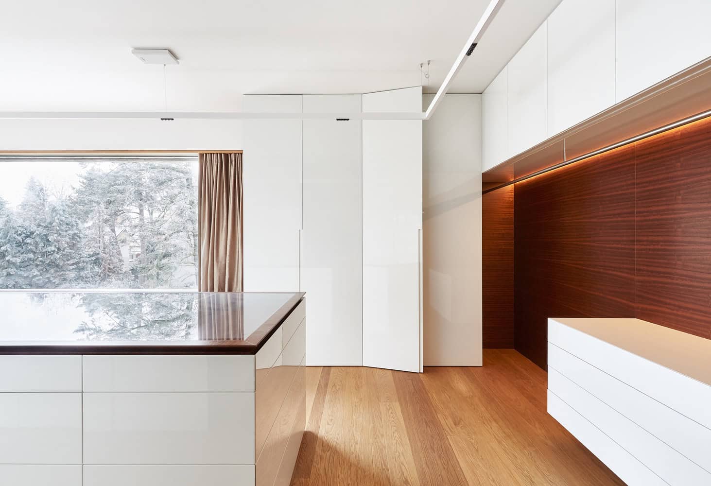 Villa Vista kitchen with glossy white cabinets and wood accents by Znameni Ctyr Architekti in Prague