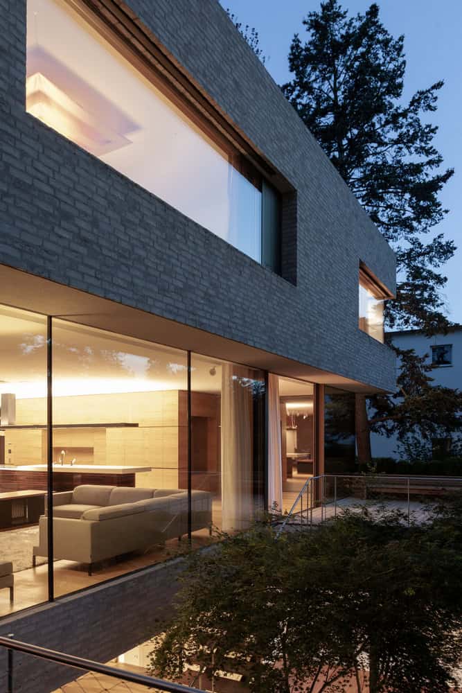 Villa Vista by Znameni Ctyr Architekti, dusk view into open-plan kitchen and living area through full-height glazing