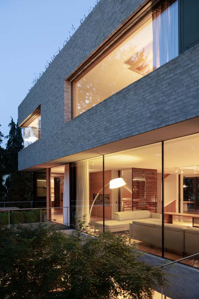 Villa Vista by Znameni Ctyr Architekti, evening view into glazed living room with warm interior lighting
