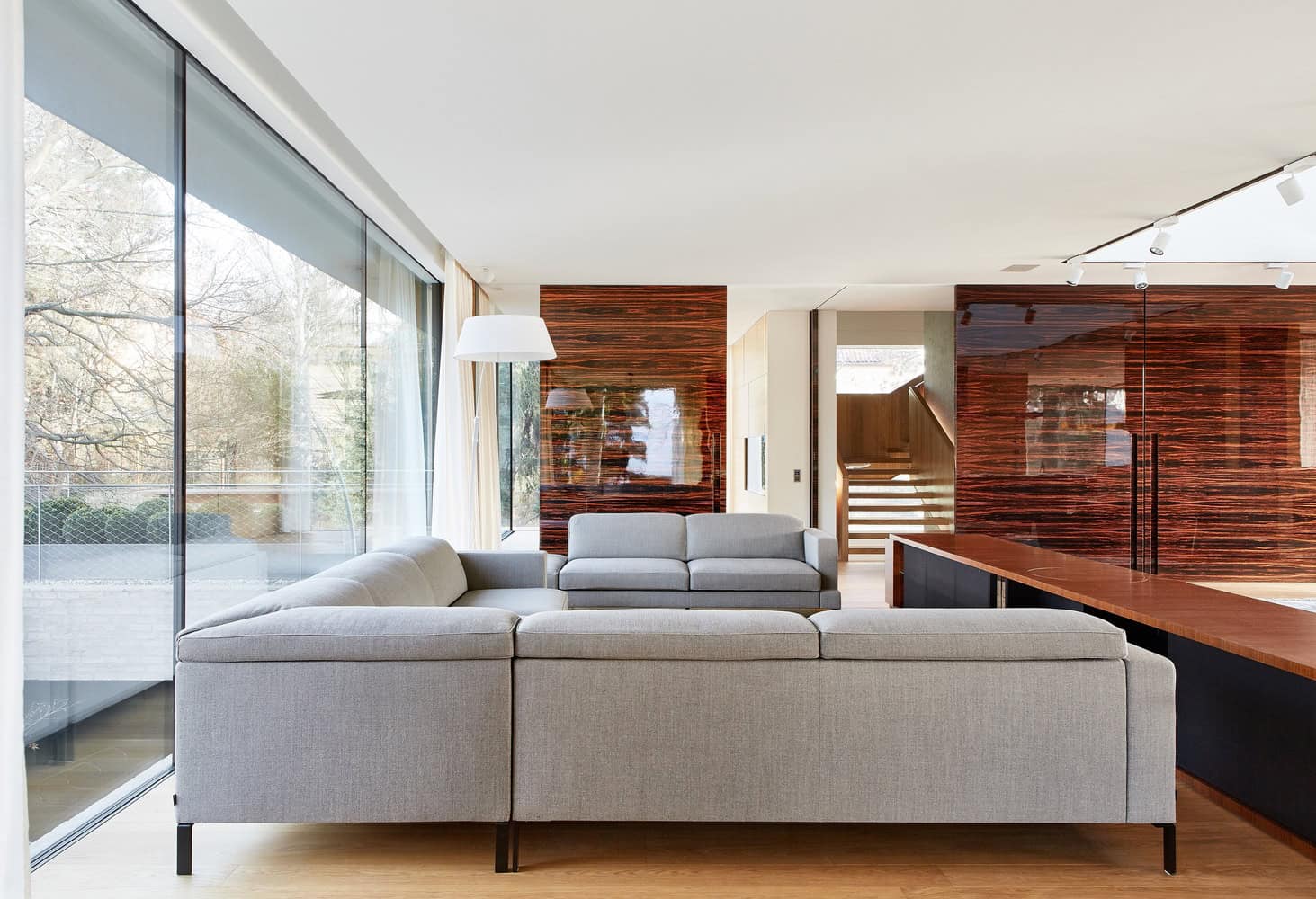 Villa Vista living room by Znameni Ctyr Architekti in Prague with grey sofas and glossy wood wall panels