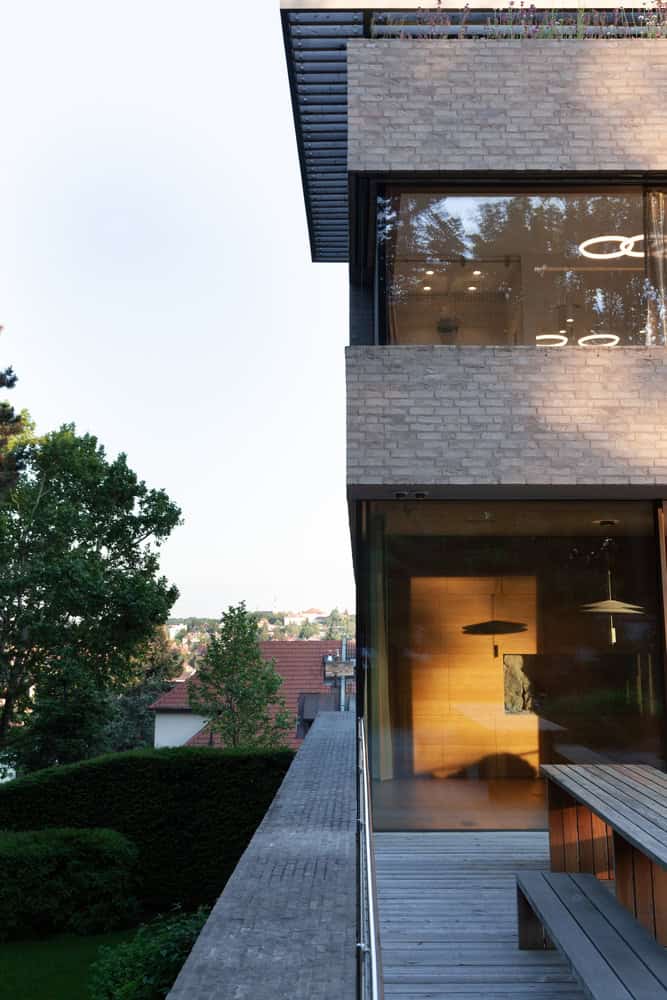 Villa Vista by Znameni Ctyr Architekti, side terrace with timber bench and long city view